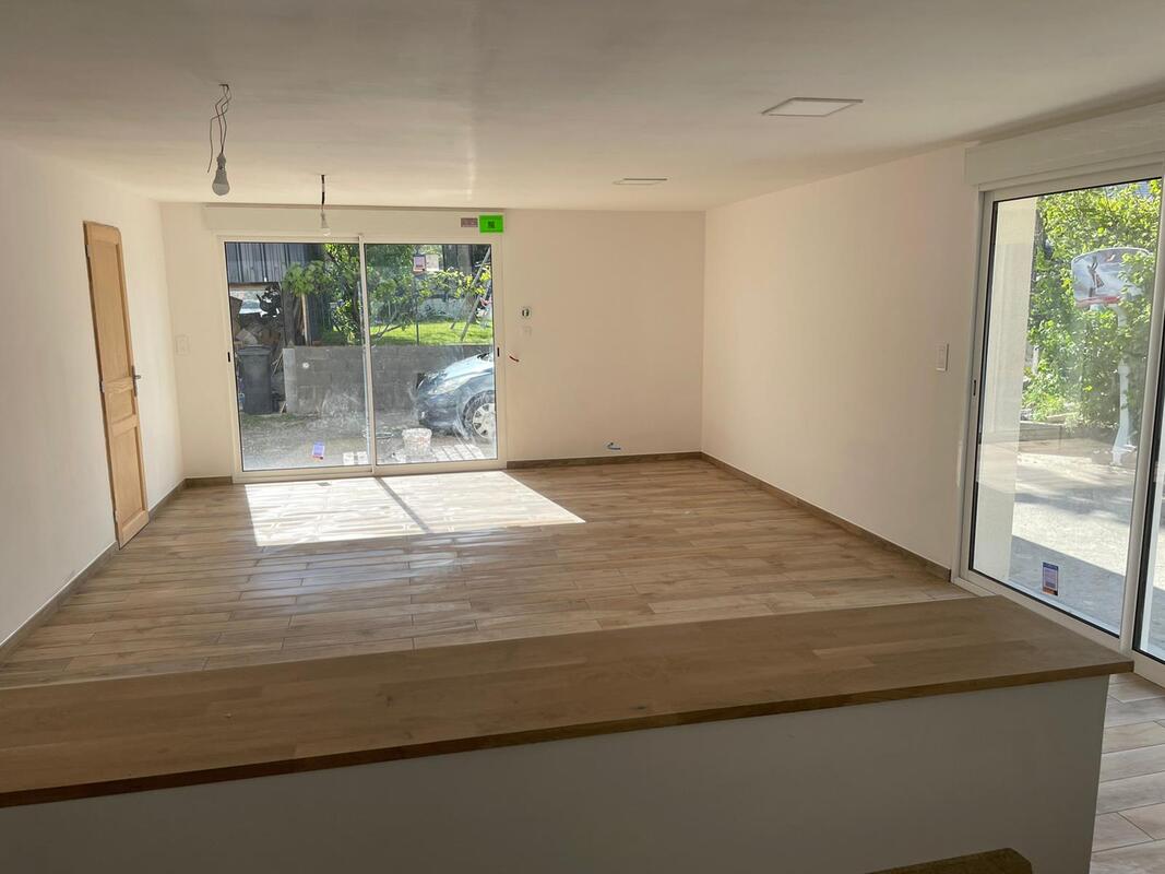 Pièce rénovée — parquet et baies vitrées par Rénov'Appart 53